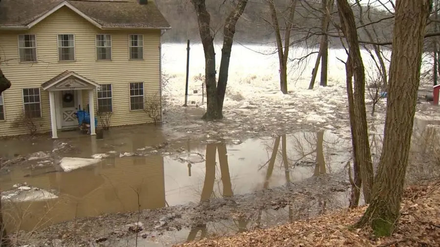 River water and broken ice around a two-story frame house after an ice jam, a flood pattern Monroe knows