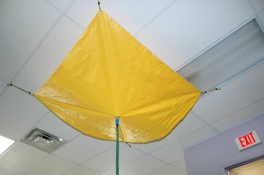Monroe commercial water damage: a leak diverter tarp catching water under a drop ceiling