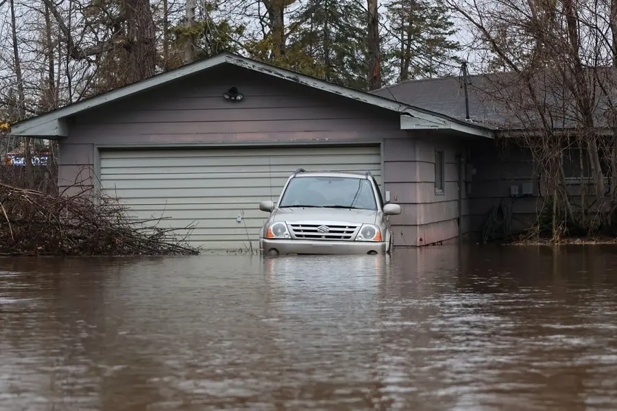 Monroe river and lake flood cleanup: flood water at a garage door with a car half under water