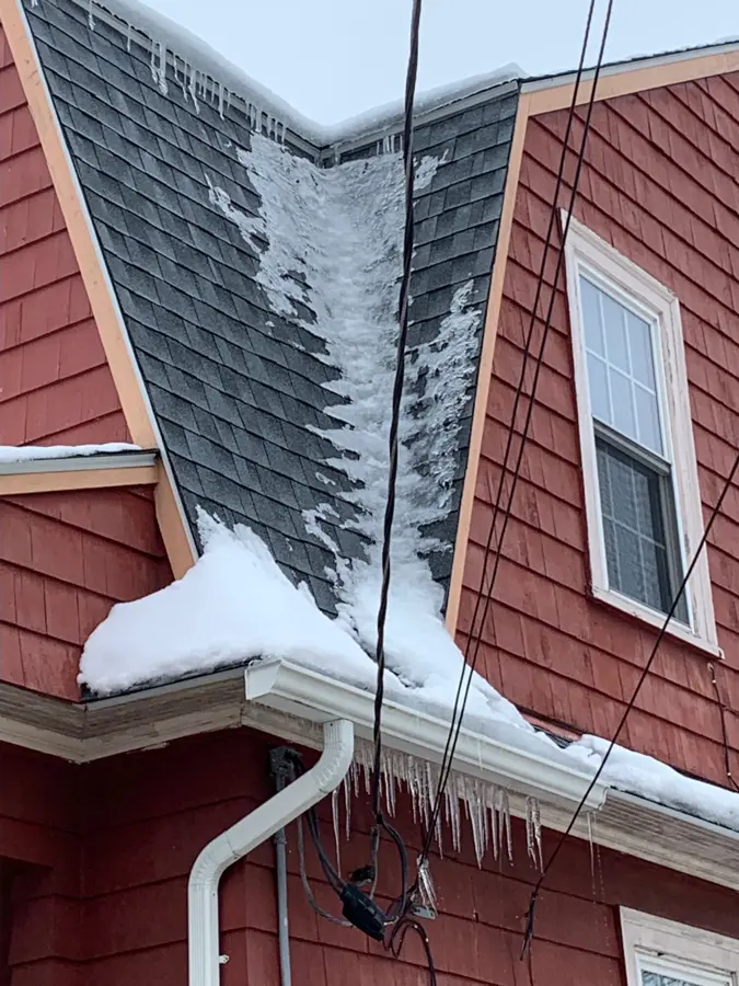Monroe ice dam water damage: snow and ice packed along a roof edge and gutter
